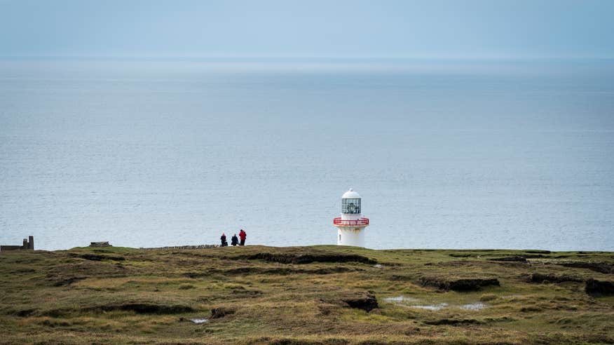 People standing at the lighthouse on Arranmore Island in Donegal