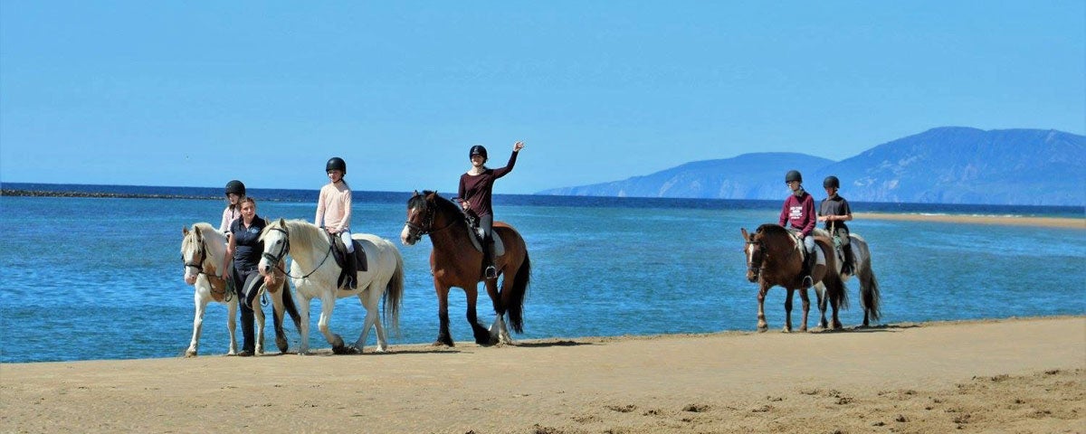 A group of children on a beach trek blue water and hills in the background